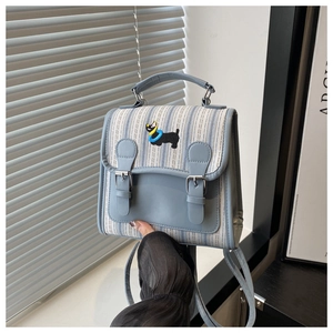Détail du sac à dos rayé bleu clair avec broderie de chien et boucles argentées