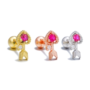 Detailed macro view of heart-shaped ear studs with red gemstones in gold and silver finishes