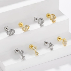 Hamsa hand and key cubic zirconia stud earrings in gold and silver on white steps