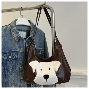 Détail d'un sac cabas en cuir marron avec broderie chiot en peluche et fermeture éclair