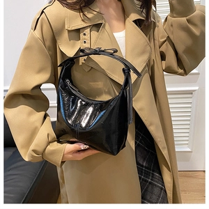 Schwarze Lackleder Hobo-Tasche mit Schleifendetail am Riemen kombiniert mit einem Trenchcoat