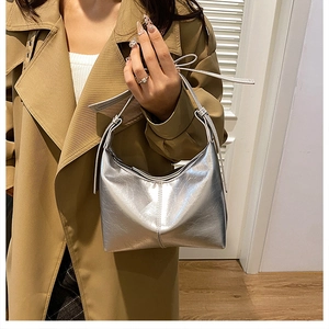 Détail du sac argenté métallisé avec texture froncée et boucle en métal réglable sur bandoulière