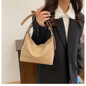 Détail du sac à bandoulière en cuir verni abricot avec bandoulière réglable et fermeture éclair