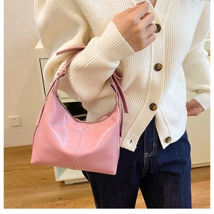 Nahaufnahme der rosa glänzenden Hobo-Tasche aus Lackleder von Modell getragen