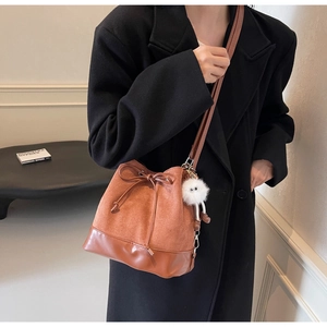 Brown bucket bag detail featuring suede texture, drawstring bow, and cute plush charm