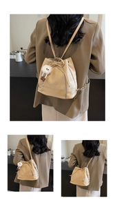 Detail of beige bucket bag with drawstring closure and plush monster charm decoration