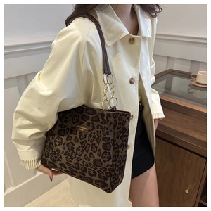 Detail of leopard print tote bag with leather logo tag and gold ring hardware accents
