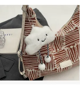Detail of striped canvas tote bag with white leather straps and cloud charm
