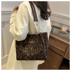 Close-up of leopard print tote bag featuring a gold chain strap and brand logo patch