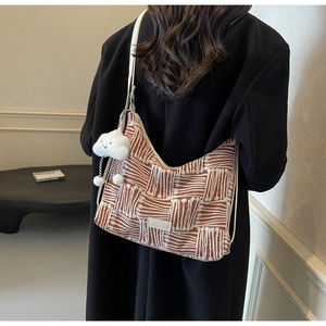Detail of canvas tote bag with geometric lines, fashion tag, and plush cloud charm