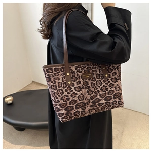 Detailed shot of leopard print canvas tote bag with brown leather handles and brand patch