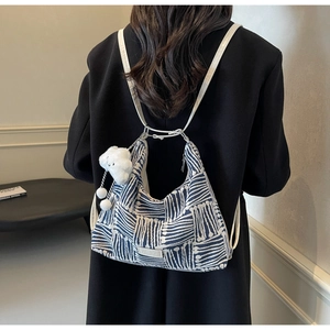 Detail of blue and white striped canvas tote bag with cute cloud charm on black coat