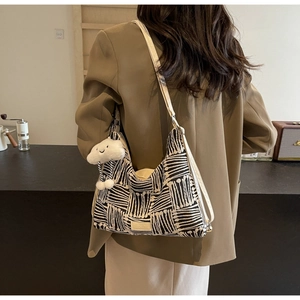 Striped canvas tote bag with cloud charm and strap shown on a model in a retro setting