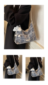 Close-up of blue and white striped woven canvas tote bag with white cloud plush pendant