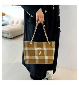 Detail of plaid wool tote bag featuring a golden chain handle and small deer pendant