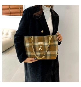 Detail of checkered crossbody bag with golden chain strap and deer charm on wool coat