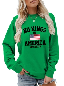 Detail of green crewneck sweatshirt featuring No Kings in America 1776 graphic print