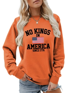 Detail of the high-quality screen print NO KINGS IN AMERICA on bright orange sweatshirt