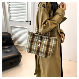 Vintage plaid tote bag with gold chain strap and deer pendant worn with a trench coat