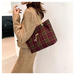 Vintage plaid tote bag with gold chain strap and deer charm shown on model in studio