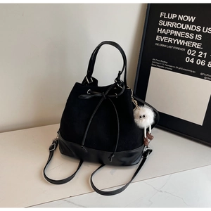 Detail of black drawstring bucket bag with velvet texture and plush monster charm