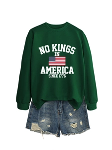 Detail of green crewneck sweatshirt with No Kings in America slogan and denim shorts