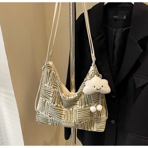 Detail of striped canvas tote with plush cloud charm and durable wide shoulder strap