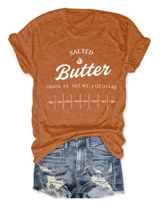 Flat lay of an orange cotton T-shirt with Salted Butter print and denim shorts