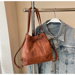 Detail of caramel brown velvet bucket bag featuring drawstring bow and dual straps