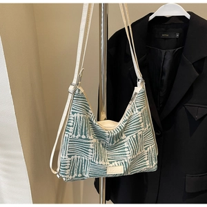 Detail of green striped knit tote bag with adjustable strap and Fashion leather label