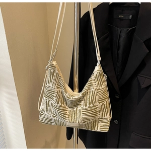 Detail of woven striped canvas tote bag in olive green and beige with silver logo plate