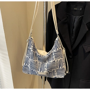 Detail view of large striped canvas tote bag with blue geometric pattern and fashion label