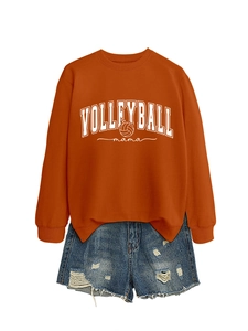 Flat lay of an orange Volleyball Mama sweatshirt paired with ripped denim shorts on white
