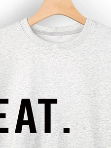Detail of grey crewneck sweatshirt featuring black EAT. printed text and ribbed neckline