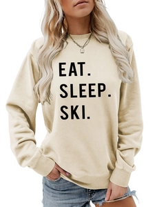 Close-up of Eat Sleep Ski black lettering on women's cream crewneck sweatshirt