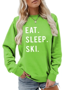 Detail view of the ribbed cuffs and white 'EAT. SLEEP. SKI.' print on bright green sweatshirt