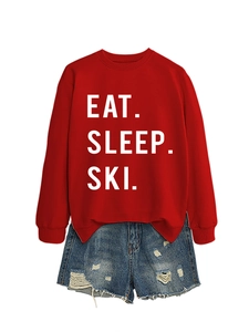 Detail of red Eat Sleep Ski sweatshirt paired with distressed blue denim shorts