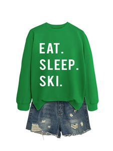 Detail of green crewneck sweatshirt with Eat Sleep Ski print and ripped denim shorts