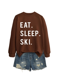 Flat lay of brown Eat Sleep Ski sweatshirt paired with distressed blue denim shorts
