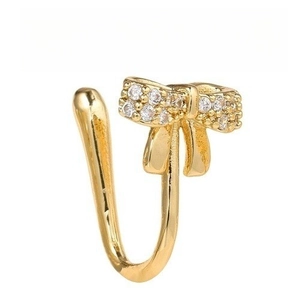 Dettaglio di un clip per naso dorato a forma di fiocco con strass scintillanti incastonati