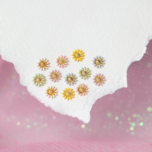 Pastel sunflower enamel earrings in six colors arranged on pink tulle backdrop