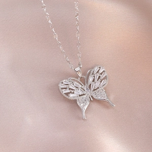 Elegant silver butterfly necklace with sparkling zircon wings on soft pink satin fabric