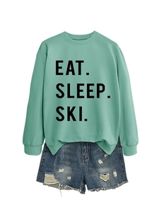 Detail of mint green sweatshirt with black Eat Sleep Ski lettering and distressed denim shorts