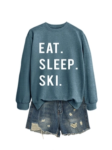 Detail of Eat Sleep Ski typography on blue sweatshirt with distressed denim shorts