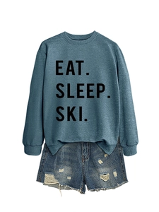Close-up of Eat Sleep Ski printed sweatshirt paired with distressed denim shorts