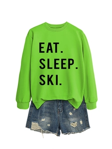 Flat lay detail of neon green Eat Sleep Ski sweatshirt with distressed blue denim shorts
