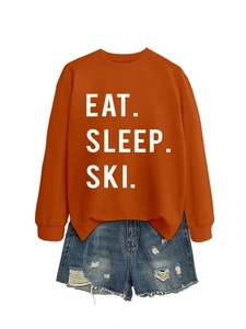Flat lay detail of orange sweatshirt with Eat Sleep Ski print and distressed denim shorts
