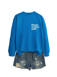 Dettaglio della felpa blu con stampa bianca e pantaloncini in denim con strappi