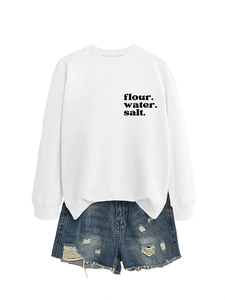 Dettaglio della felpa bianca in cotone con stampa e degli shorts in denim con strappi