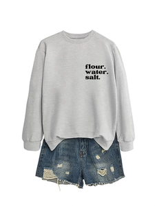 Dettaglio felpa grigia con stampa flour water salt abbinata a pantaloncini di jeans strappati